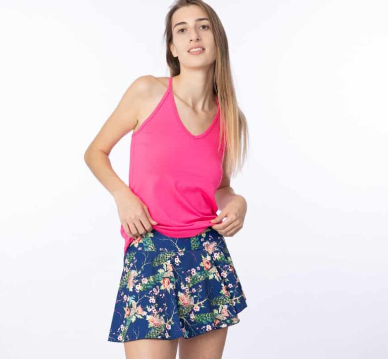 Woman wearing a v-neck pink tank top and navy blue floral wrap flair skirt.